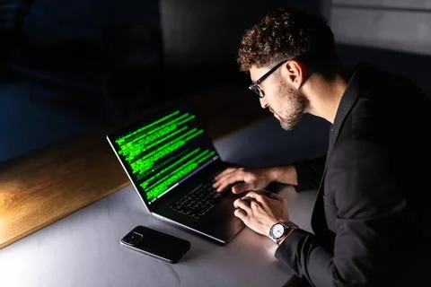 Young man mobile developer writes program code on a computer, programmer work Stockfoto's