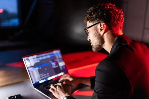 Young man mobile developer writes program code on a computer, programmer work 스톡 사진