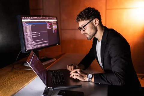Young man mobile developer writes program code on a computer, programmer work 写真素材