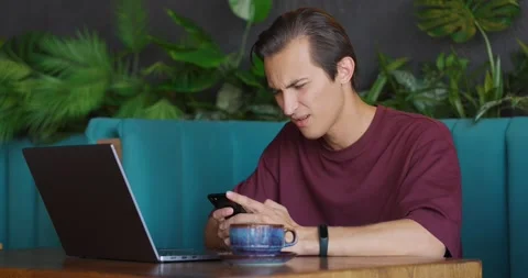 Young man with mobile phone looking upset and puzzled getting sad news.Guy Stock Footage 164600520