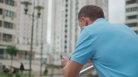Young man with mobile phone stands on the stairs near the railing, camera Stock Footage 142012306