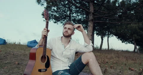 A young man model with guitar sitting down in the park, forest. Stock Footage 144502909