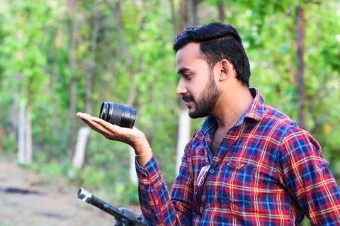 Young man model holding a camera lens with his hand side view Stock Photos