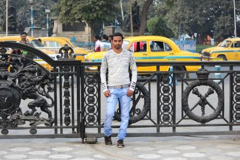 Young man model standing infront of a gate with road and taxi background Stock Photos