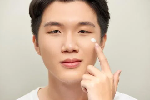 Young man with moisturizer on the face Stock Photos