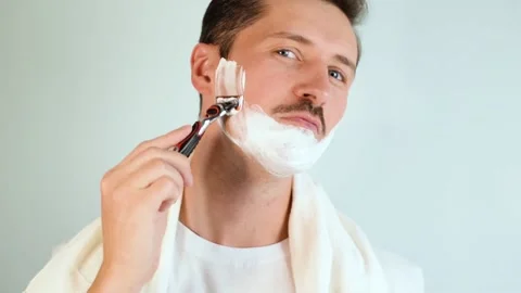 Young man moisturizing foam on face shaving with modern sharp razor 库存影片 165855460