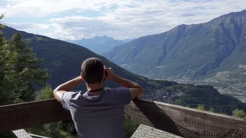 Young Man on Mountain Balcony Using Binoculars, Dolly Video stock 79006265