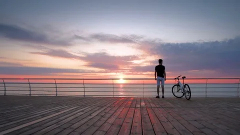 Young man with mountain bike on seafront during sunset or sunrise Stockbeeldmateriaal 75962044