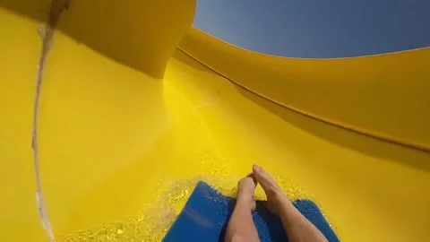 Young man moves fast along the yellow water slide of the water park. Stock Footage 157757697