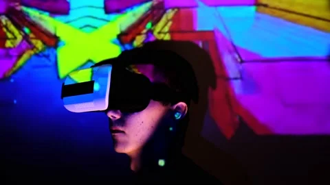 Young man moves his head relaxed. Guy rests, looking and using VR-helmet night a Stock Footage 130180256