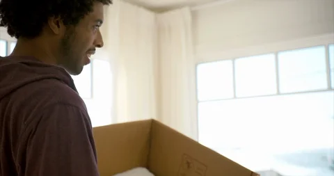 Young man moving a box into his new home. Vidéo 93864015