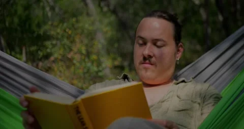 Young Man With Mustache And Earring Reading Book... Stock Footage 331820770