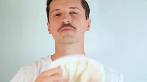 Young man with mustache in bathroom looking at camera wipes  face after shaving Vidéo 165855462