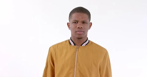 Young man in mustard jacket looking confused against white background Stock Footage 346296103
