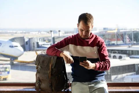 Young man navigates with his phone while waiting for his flight to leave Stock Photos