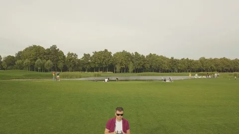 Young man navigating a flying drone with remote control. Man in countryside f Stock Footage 95208397