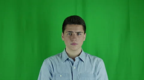 Young man is nervous in front of a greenscreen in a blue shirt Vidéo 59082745