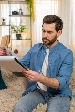 Young man nervously flips through papers and bills, searching for something Foto stock