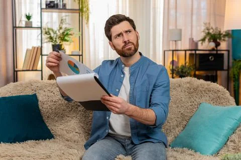 Young man nervously flips through papers and bills, searching for something Stock Photos