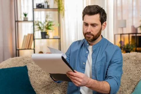Young man nervously flips through papers and bills, searching for something Stock Photos