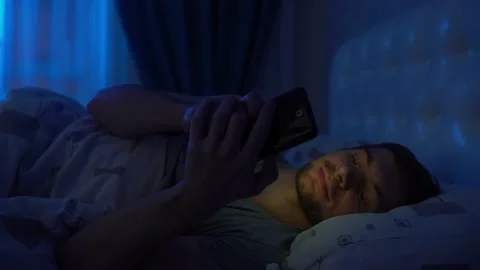 Young man at night in bed looking into a smartphone Stock Footage 152529320