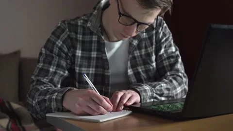 A young man notes an online lecture in a notebook. distance education. slide. Stock Footage 236689789
