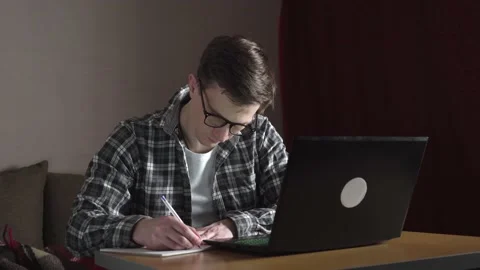 A young man notes an online lecture in a notebook. distance education. Stock Footage 237450849