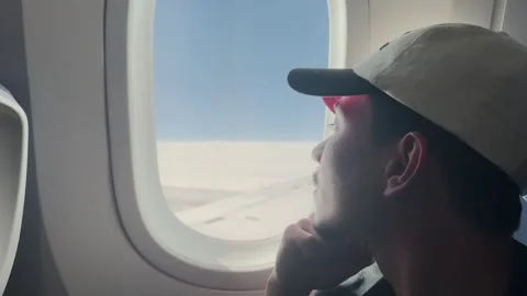 Young man observing the aerial view through the airplane window Stock Footage 319348410