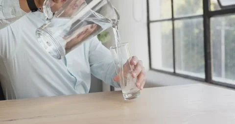 Young man in office drinking water from glass, staying hydrated at work Stock Footage 346145624