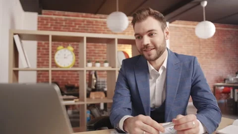 Young man in the office having a video conversation in a laptop 動画素材 194363608