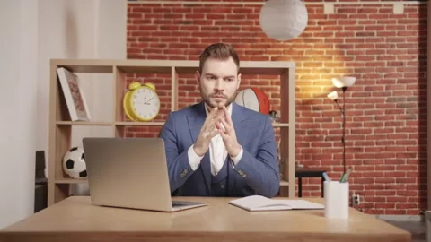 A young man in the office sits thoughtfully and motionless and thinks. Stockbeeldmateriaal 194365724