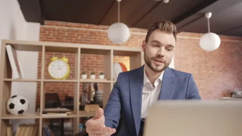 A young man in the office is talking to someone on a video in a laptop Vidéo 188778133