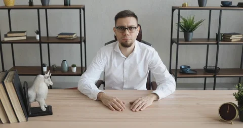 Young man office worker in glasses sitting at table and looking at camera. Stock Footage 120835670