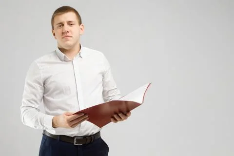 Young man with an open folder in his hands isolated on a light background Stock Photos