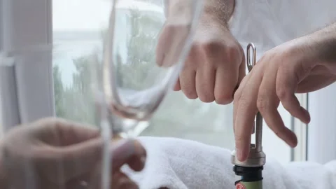Young man opening bottle of wine while standing in kitchen at home. Close up of  Stock Footage 263727592