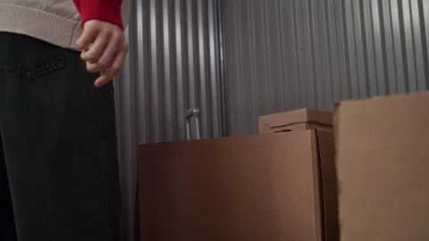 Young Man Opening Box and Examining Belongings in Self Storage Unit Stock Footage 327783253
