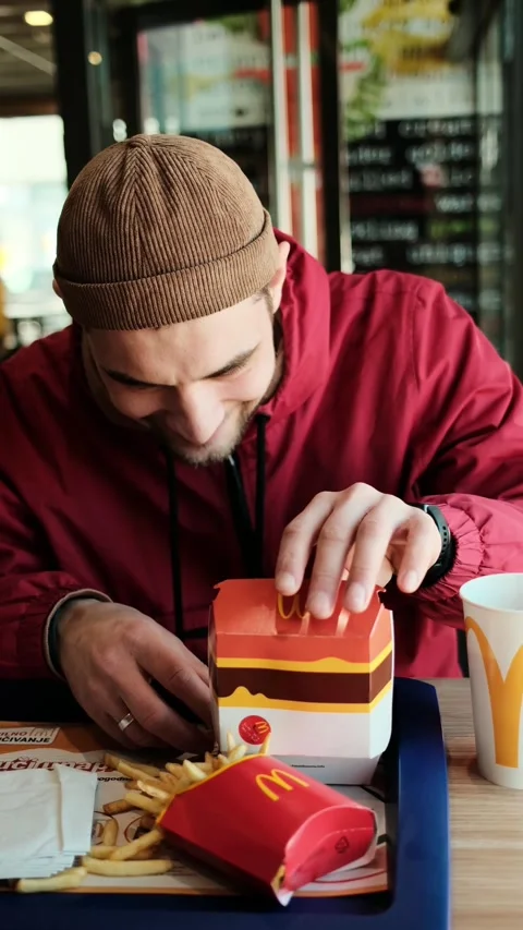 Young man opening a burger box and taking a juicy bacon beef burger on a sesame Stock Footage 341968376
