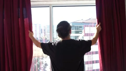 Young man opening the curtains Stock Footage 257498522