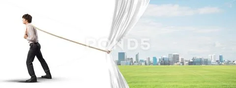 Young man opening white curtain and presenting modern city landscape Stock Photos
