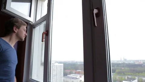 Young man is opening window and watching out. high floor. Up point Stock Footage 76116414