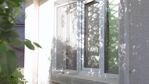 Young man opening window toward garden and getting fresh air; view from outside Stock Footage 81657479