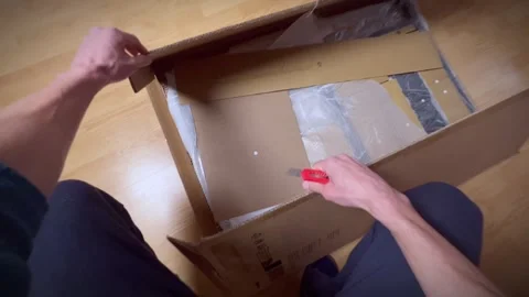 A young man opens and unpacks a box with a disassembled table Stock Footage 240954331