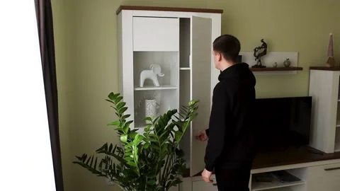 A young man opens a cabinet and takes out a bottle of pills. Stock Footage 231814157