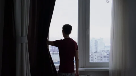 A young man opens the curtains 库存影片 87708580