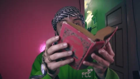 A young man opens the Holy Quran in his home Stock Footage 299576141