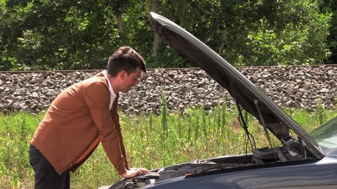A young man opens the hood of a broken car. Stock Footage 113399145