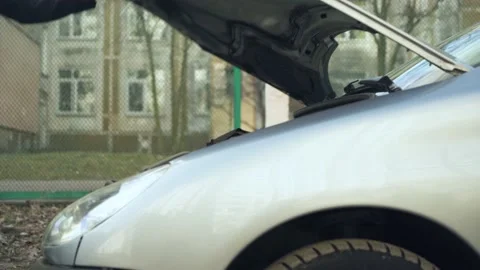 Young man opens the hood of his car. car breakdown. city street. Stock Footage 233355438
