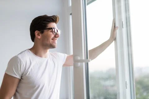 Young man opens the window. Ventilating a house in hot weather. Stock Photos
