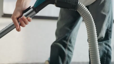 Young man operates vacuum to clean textured carpet fibers. Person uses power Stock Footage 337463422