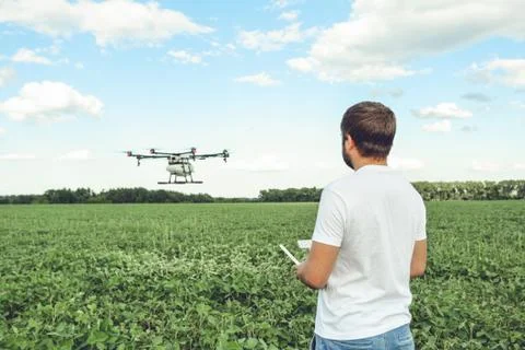 Young man operating of flying drone octocopter at the green field. Foto stock